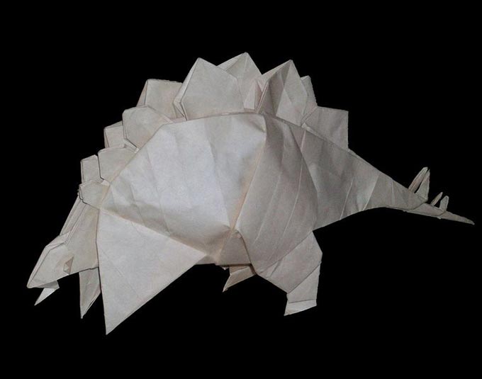 This picture shows a close up view of a finished piece of Stegosaurus origami set against a black background.