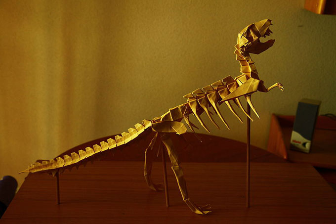 This photo shows an impressively constructed Tyrannosaurus rex origami model standing on a desk.