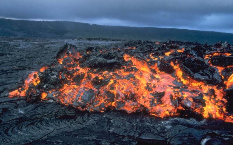 A close up photo of a lava flow as it makes its way from a volcano crater after a recent eruption.