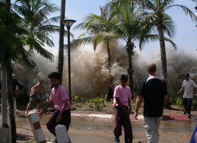 An incredible scene from the 2004 tsunami in Thailand has been captured in this memorable photo. As a huge wall of water bursts through the trees people begin to scatter in every direction, previously unaware of the danger that was so close by.