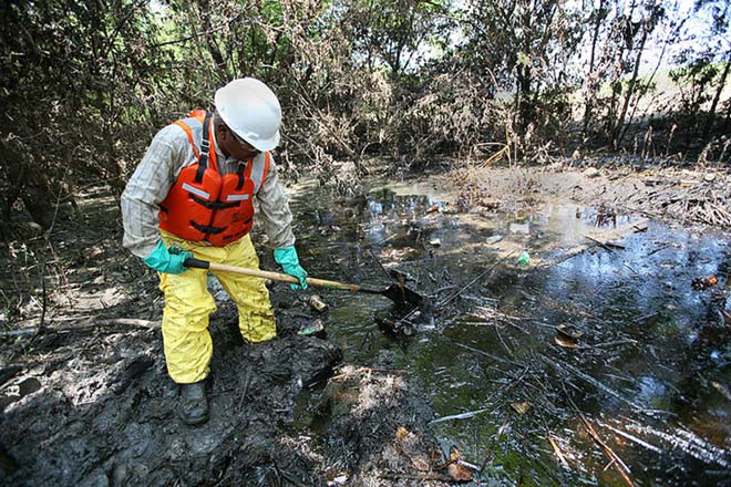 After flooding and oil contamination from a local refinery destroyed much of a nearby town, a contractor works hard to continue the oil spill cleanup job.