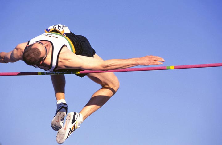 An athlete leaps high into the air and clears the bar while competing in a high jump competition.