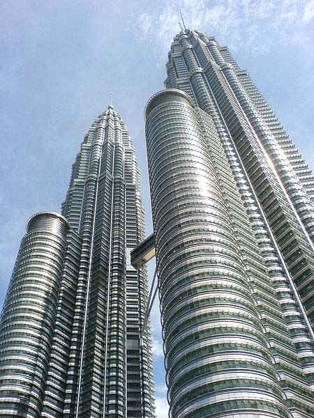 This photo is taken from the ground looking up at the impressive Petronas Towers in Kuala Lumpur, Malaysia. The twin buildings were once the tallest in the world but still remain among the tallest. They reach an incredible 452 metres (1483 feet) in height and feature 88 floors.