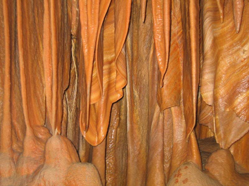 These unusually shaped stalactites hang from the roof of a cave, slowly meeting the stalagmites that extend from the floor of the same cave.