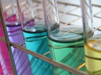 A photo showing a side on angle view of colored test tubes sitting in a rack. 