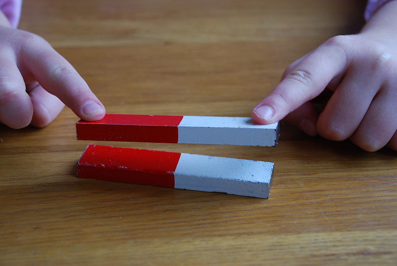 This photo clearly shows that like poles of a magnet repel each other. This effect can be quite strong. In this image, as a child holds down the top magnet down with their fingers, it looks like the top magnet is floating due to the magnetic force.