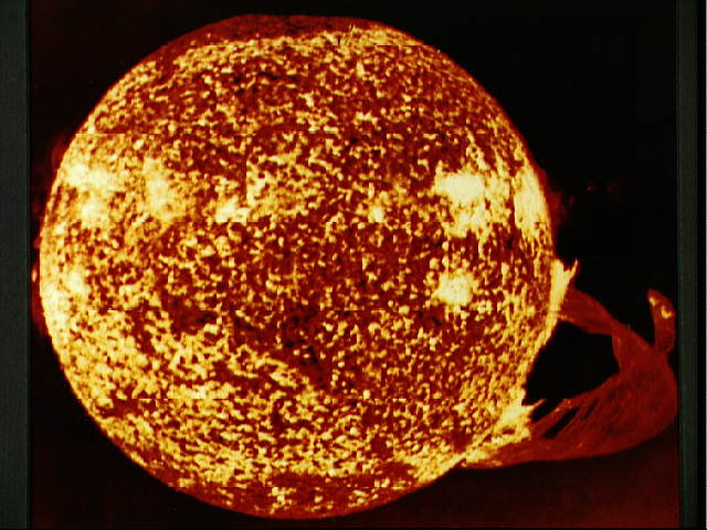A photo of the sun showing an incredible solar flare reaching out away from the glowing star.