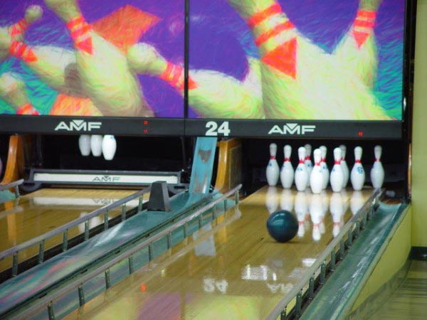 This bowling photo shows a bowling ball as it rolls down the lane towards the pins.